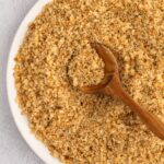 Gluten-free bread crumbs in bowl with wooden spoon.