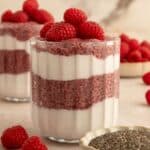 Berry chia seed pudding in jar layered with dairy-free yogurt and topped with red raspberries.