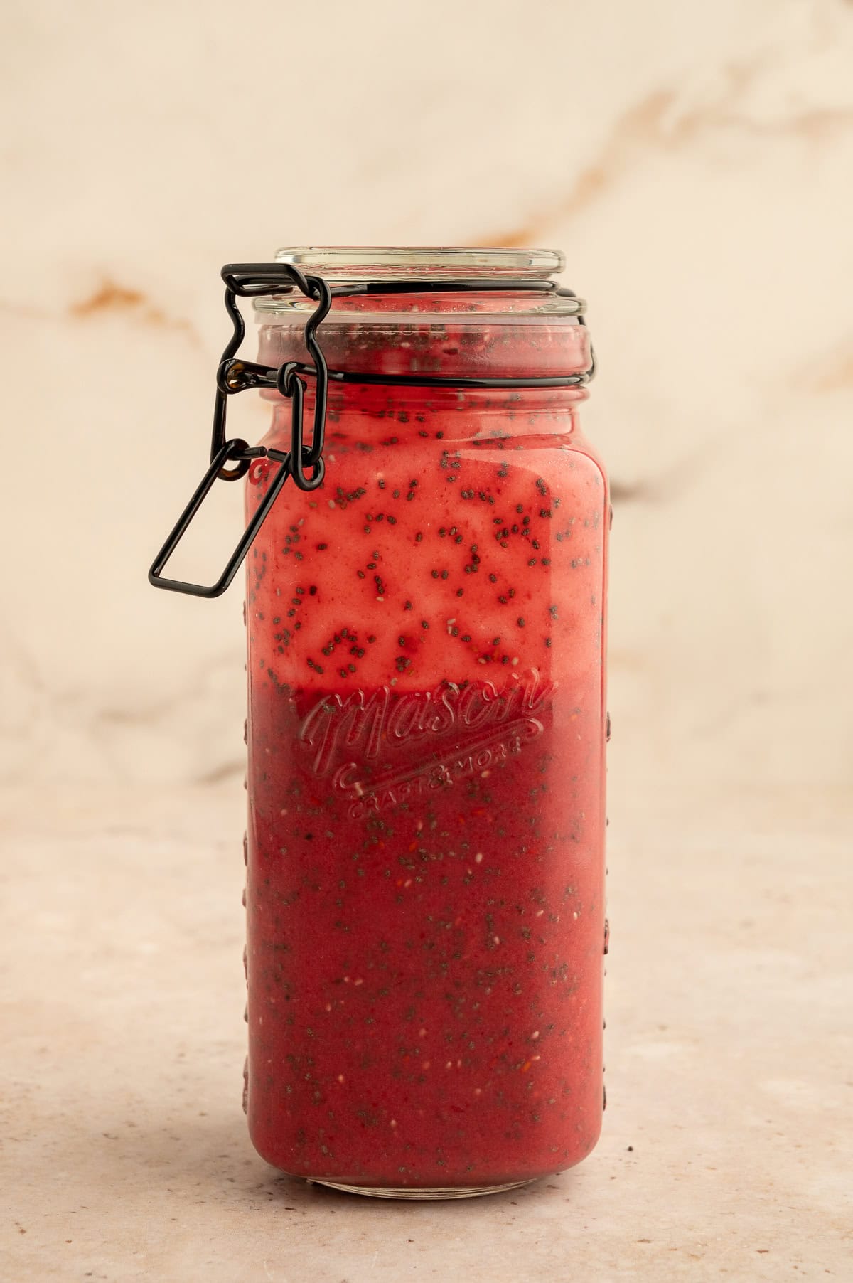 Chia seeds and berry mixture agitated in jar.