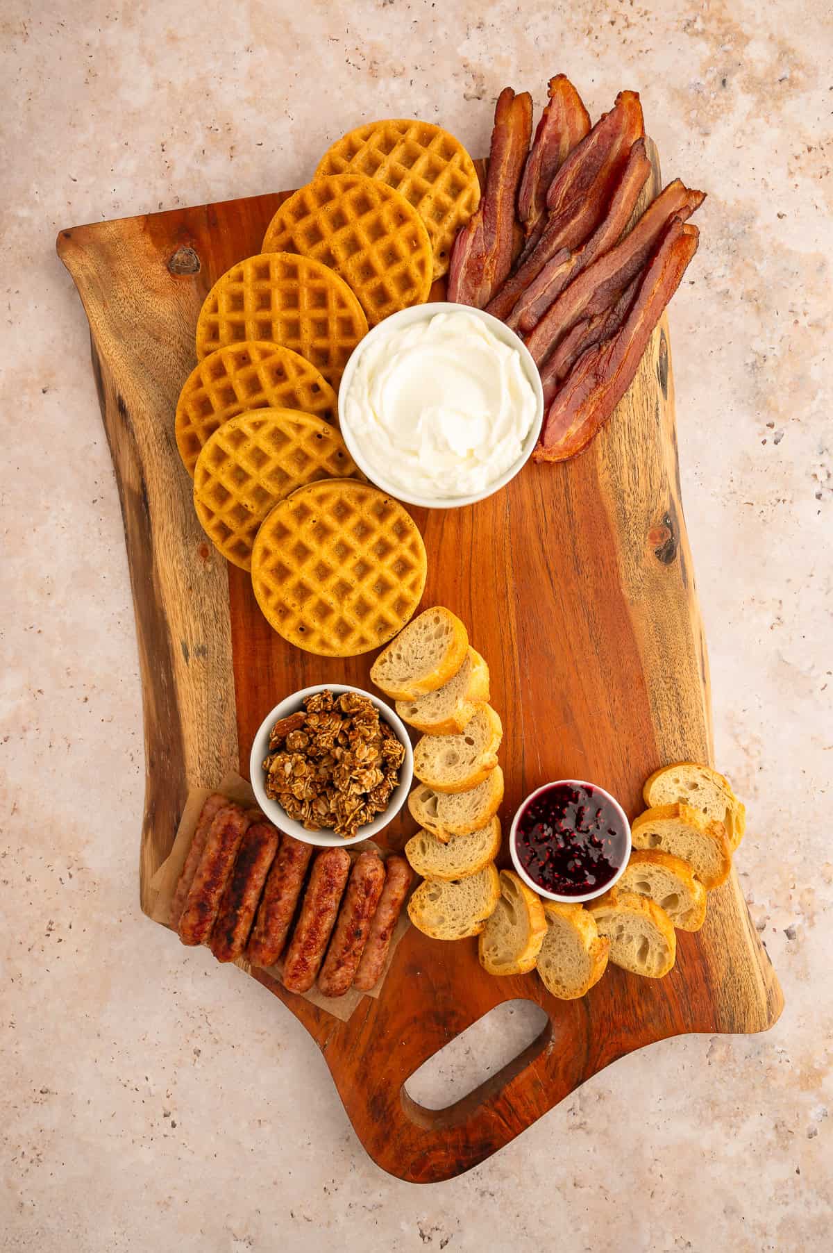 fanning around ramekins on board with meats, waffles and bread.