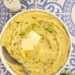 Bowl of dairy-free mashed Yukon gold potatoes topped with dairy-free butter and chives.