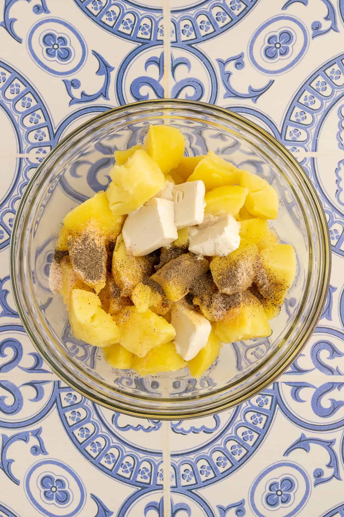 Peeling skin from the boiled potatoes and then adding dairy-free butter and seasoning.