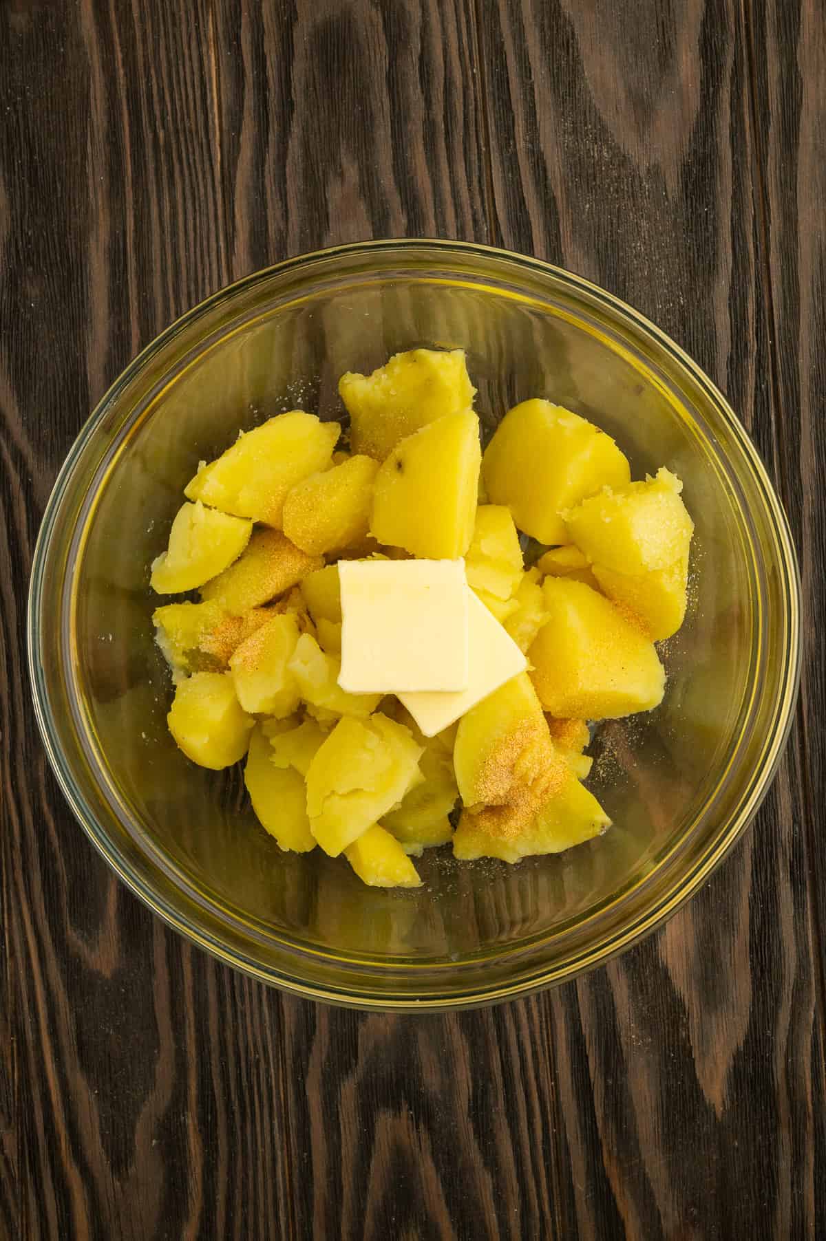 Adding butter and seasoning to boiled potatoes.