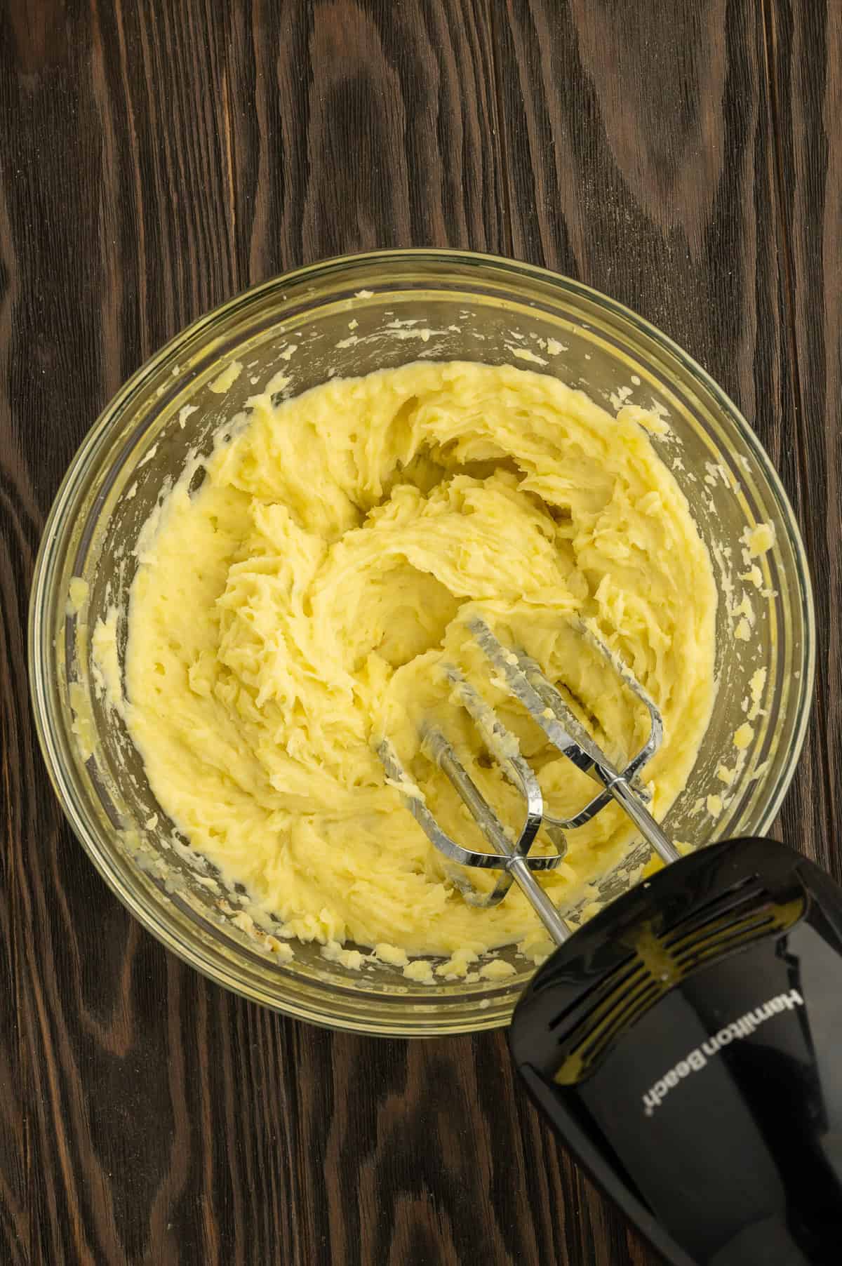 Mashing potatoes in a bowl with a handheld mixer.