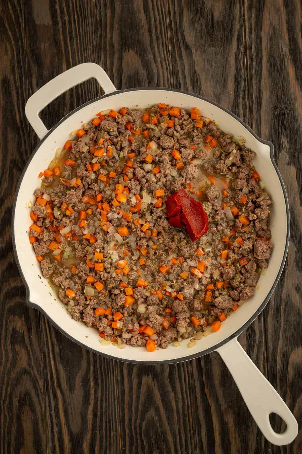 Adding tomato paste, Worcestershire sauce, and broth/starch slurry to make a sauce in the skillet with the beef.