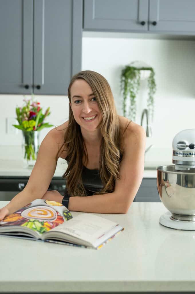 Amanda reading a cookbook bent over a counter in a kitchen.