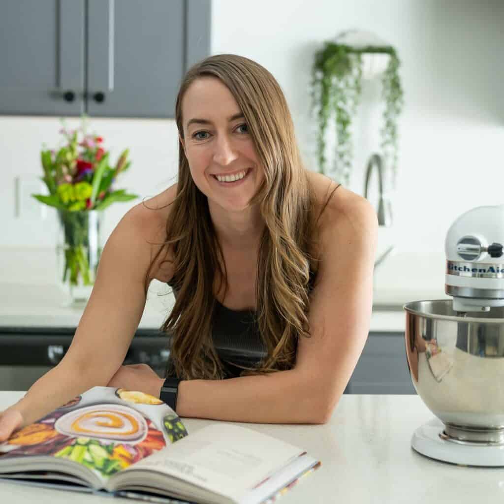 Amanda reading a cookbook bent over a counter in a kitchen.