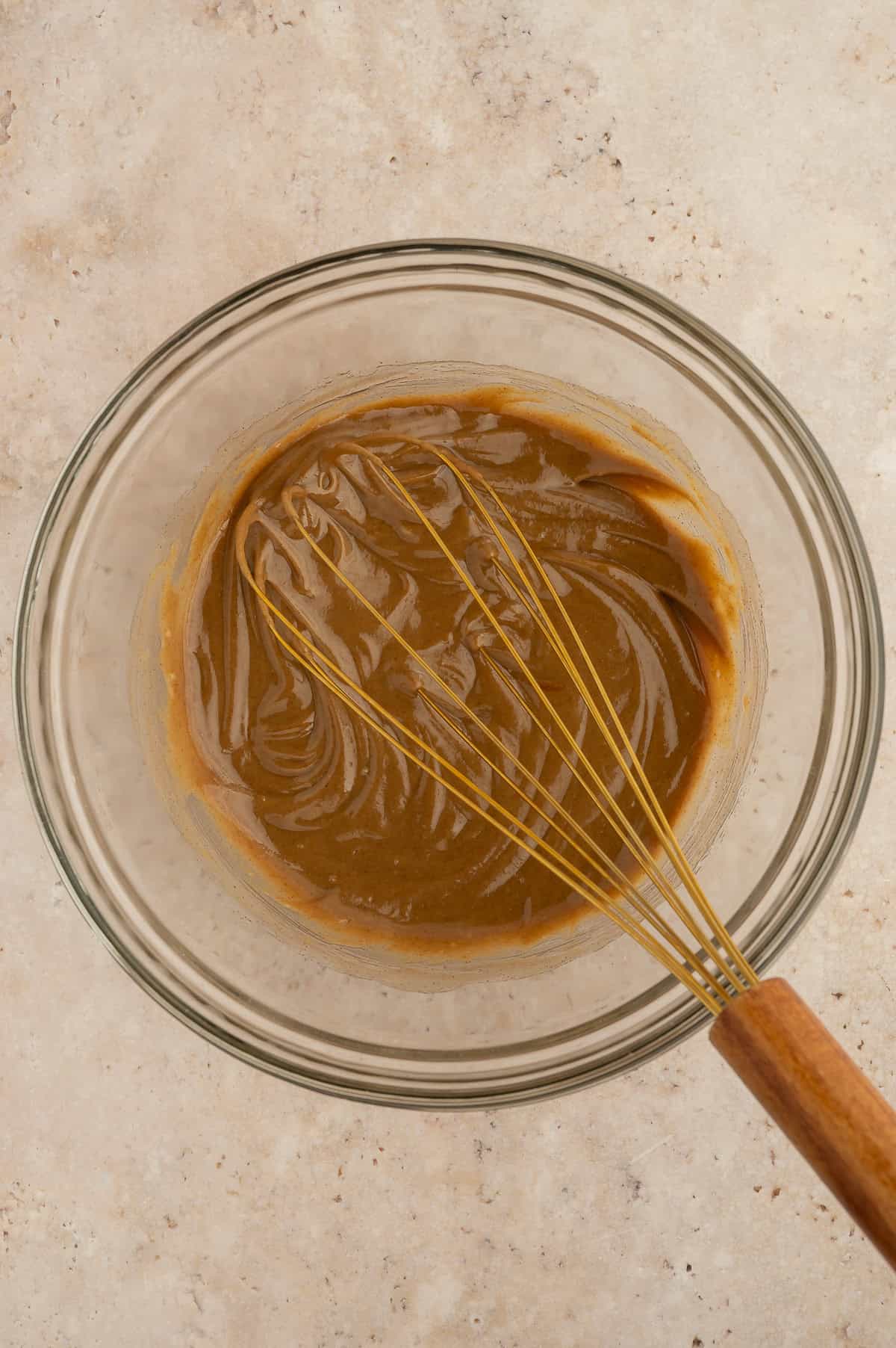 Wet ingredients being mixed together in a mixing bowl with a whisk.