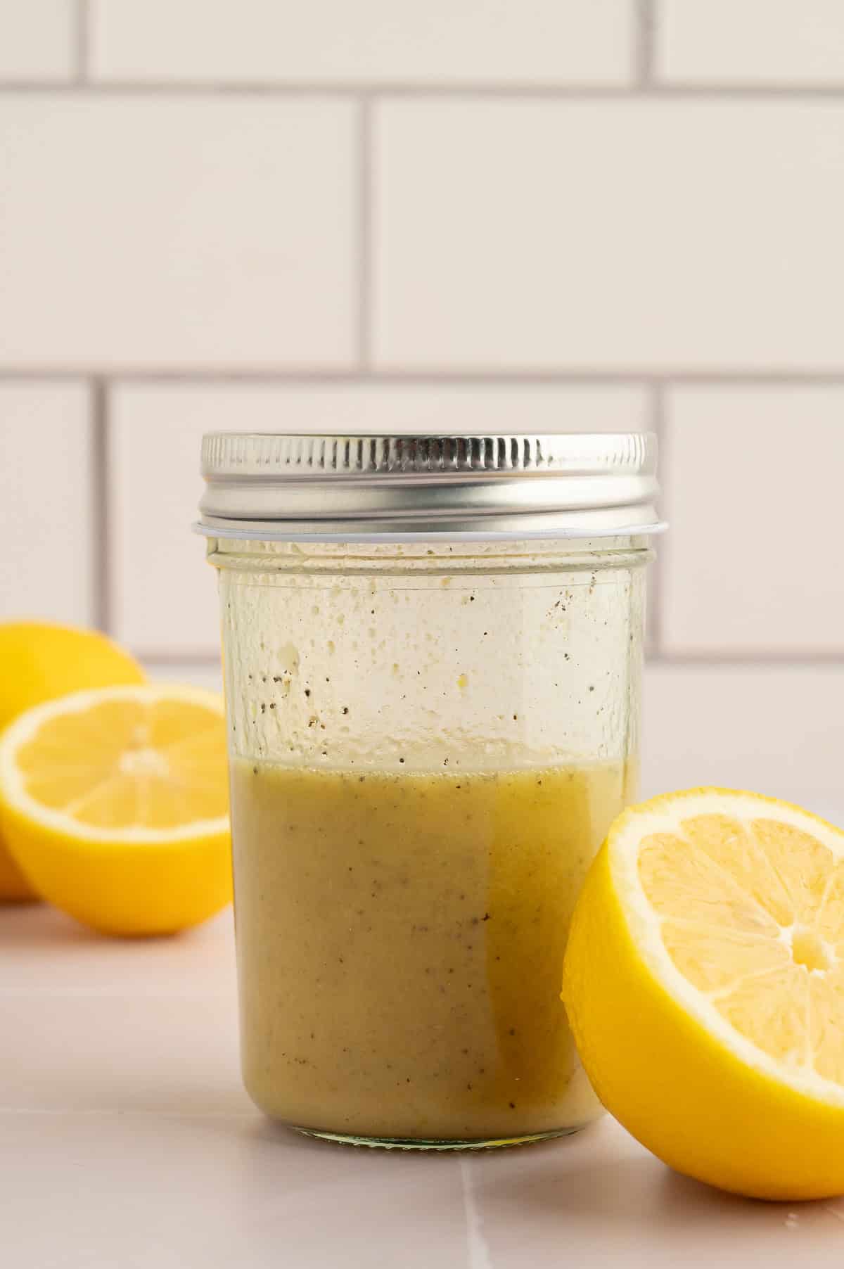 Jar of lemon vinaigrette next to lemons.