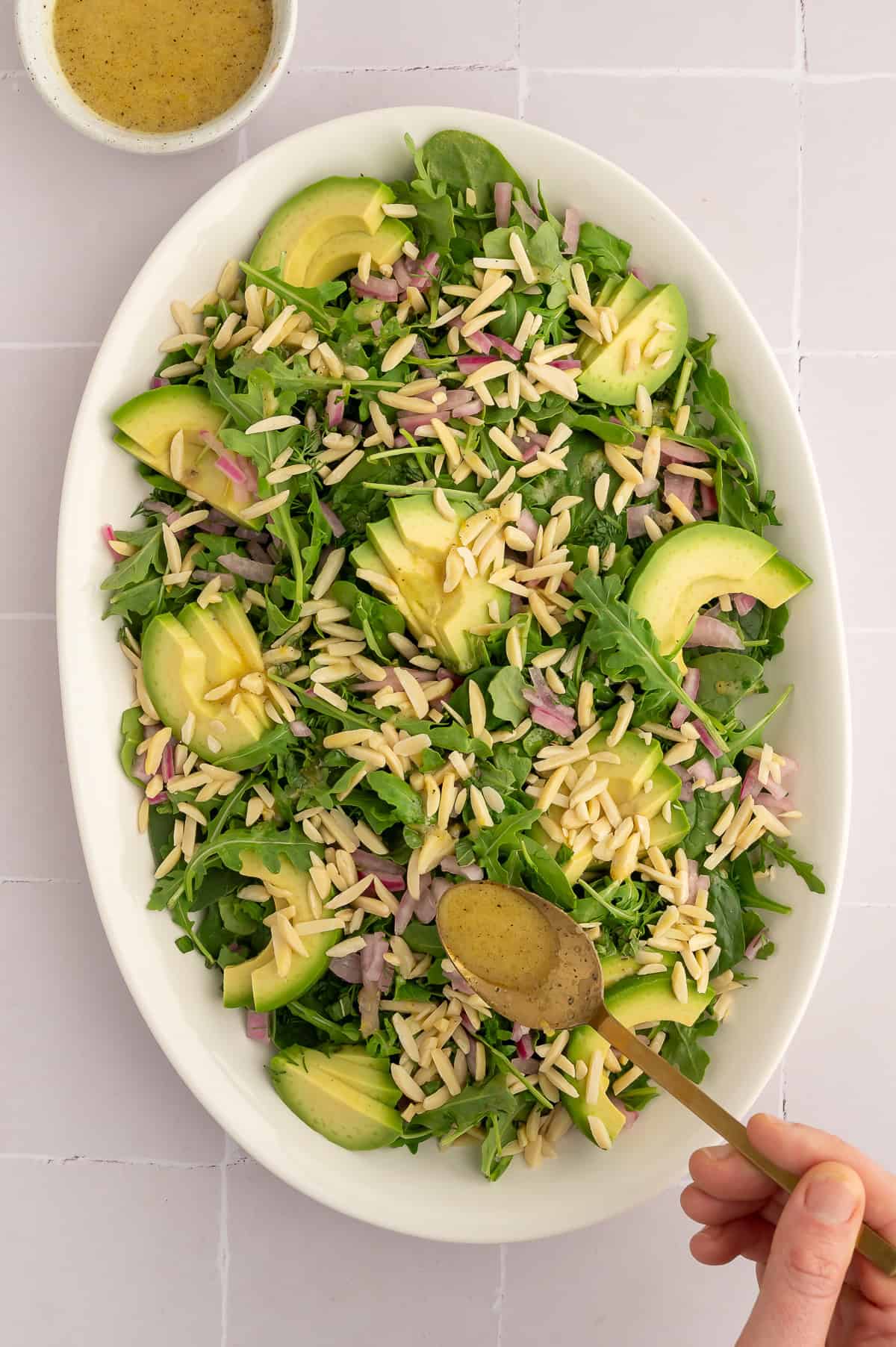 Pouring dressing on arugula and spinach salad.