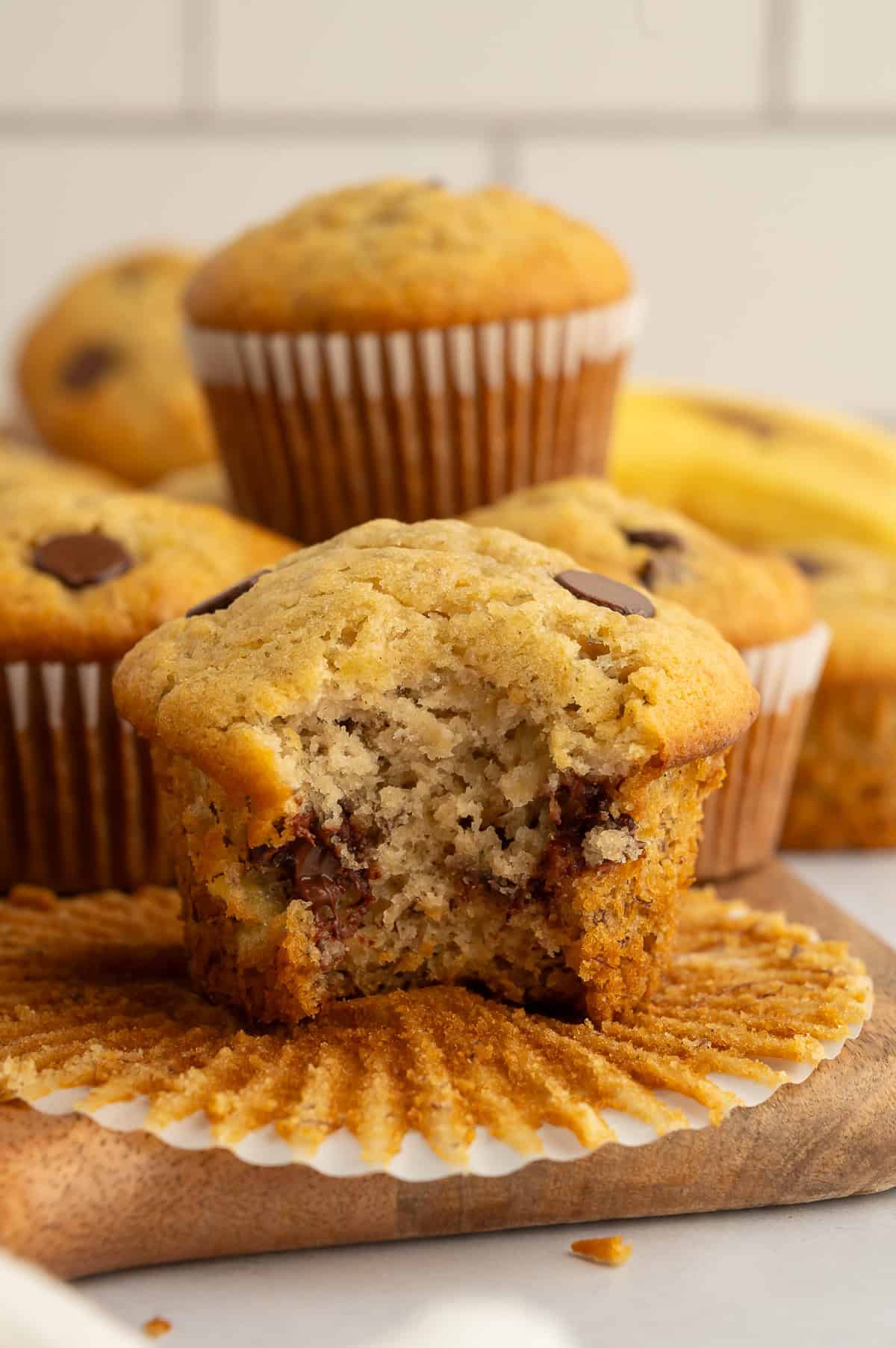 Close up of pile of gluten-free chocolate chip banana muffins, one with a bite out of it.
