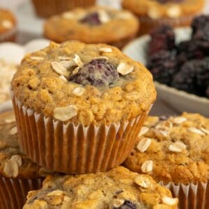 Pile of banana blackberry oatmeal muffins with oats on top.