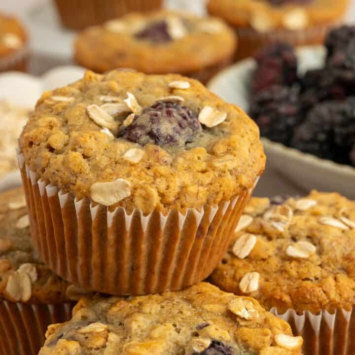 Pile of banana blackberry oatmeal muffins with oats on top.