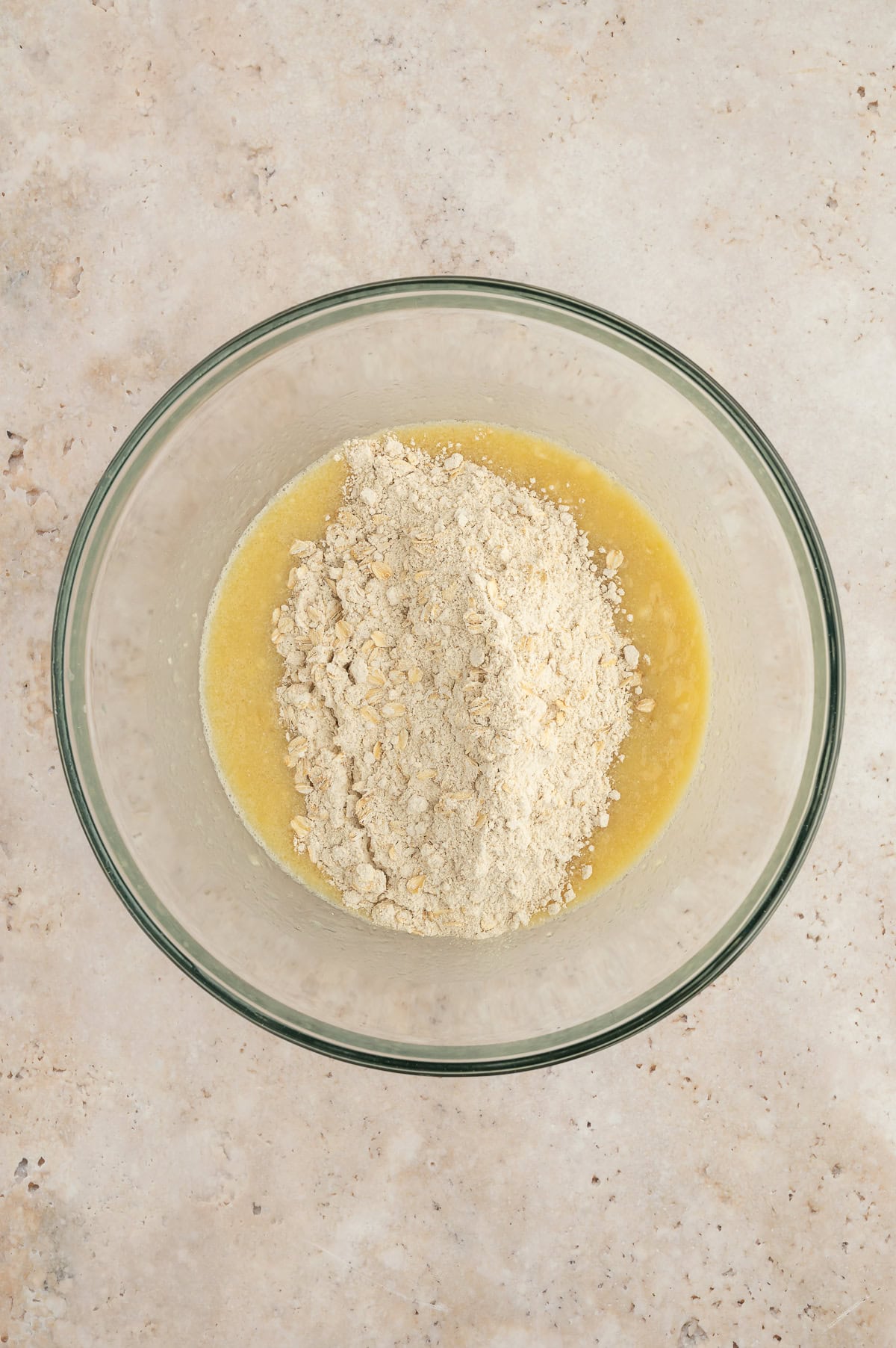 Wet and dry ingredients for banana blackberry oatmeal muffins in a mixing bowl.