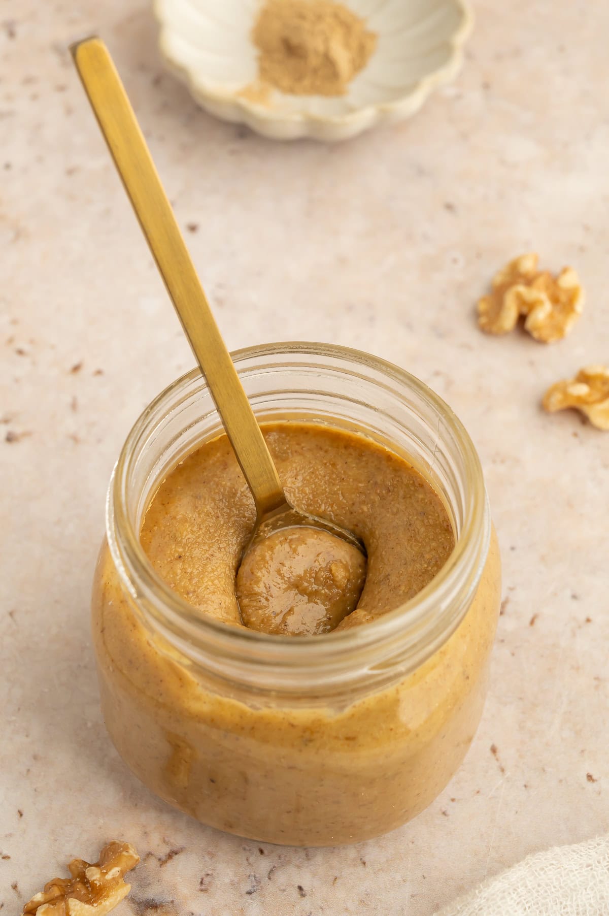 Jar of creamy walnut butter with a spoon in it.