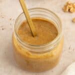 Jar of creamy walnut butter with a spoon in it.