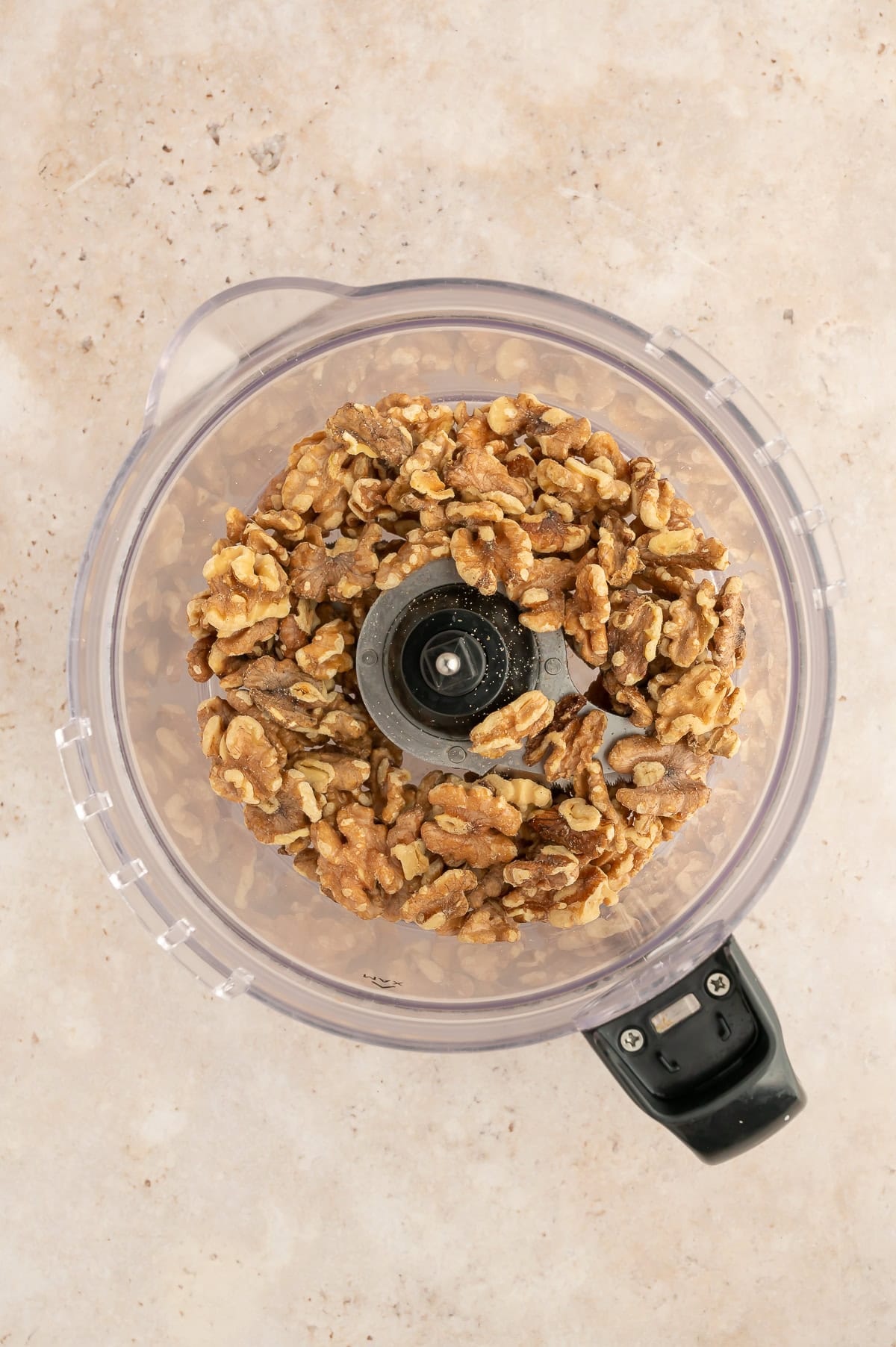 Food processor with roasted walnuts in it.