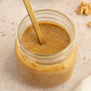 Jar of creamy walnut butter with a spoon in it.