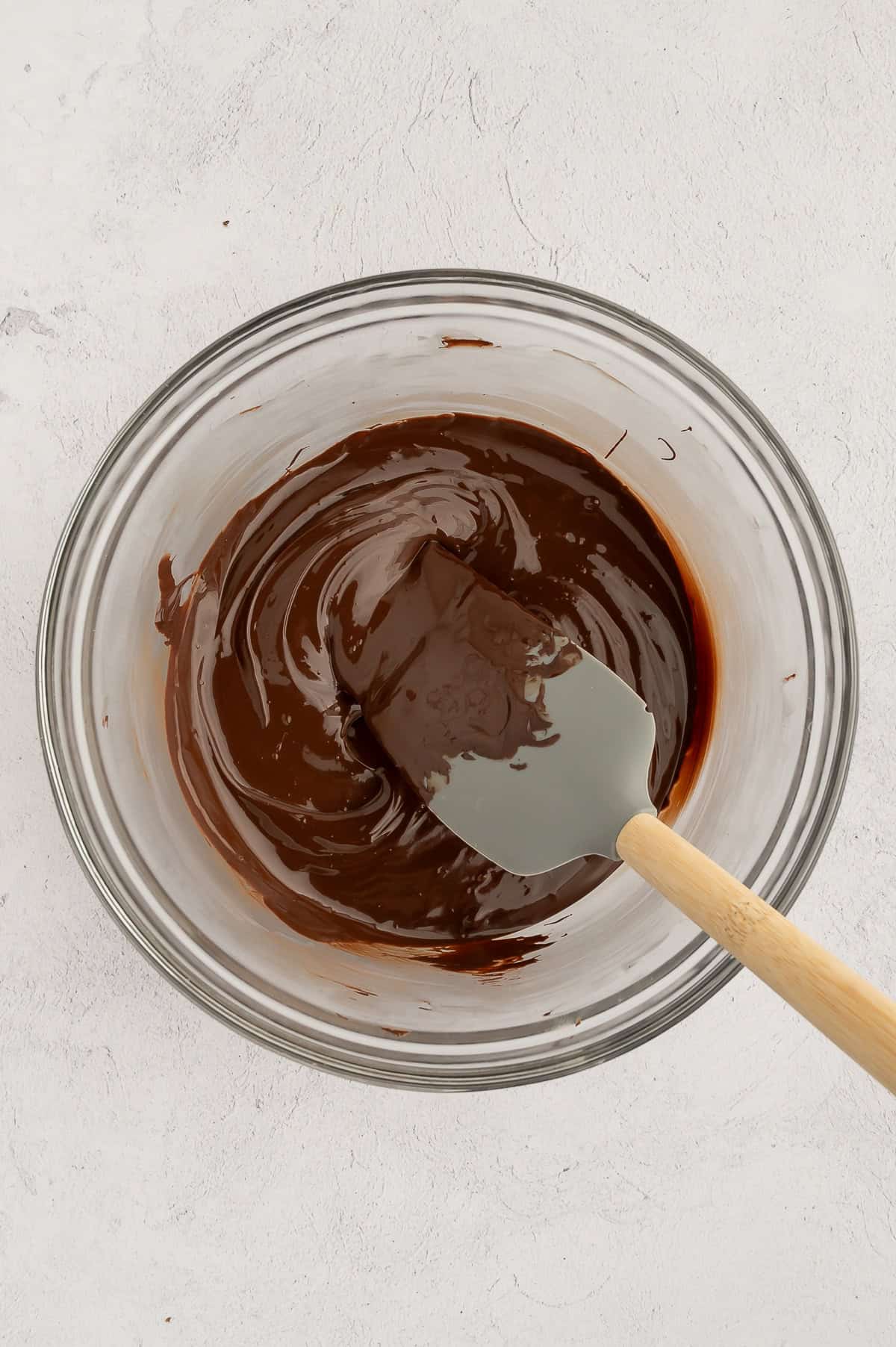 Melted chocolate chips in a bowl with a spatula in it.