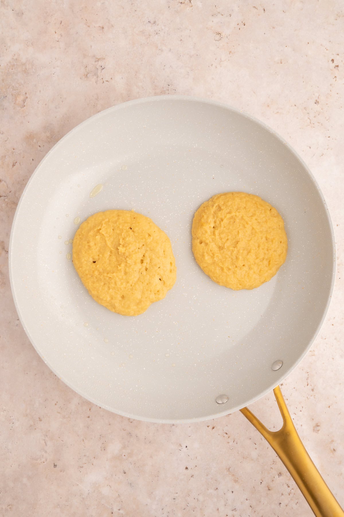 Pancake batter is beginning to cook and bubbles are forming in the batter in a skillet.