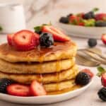 Stack of protein pancakes with dripping syrup and berries.