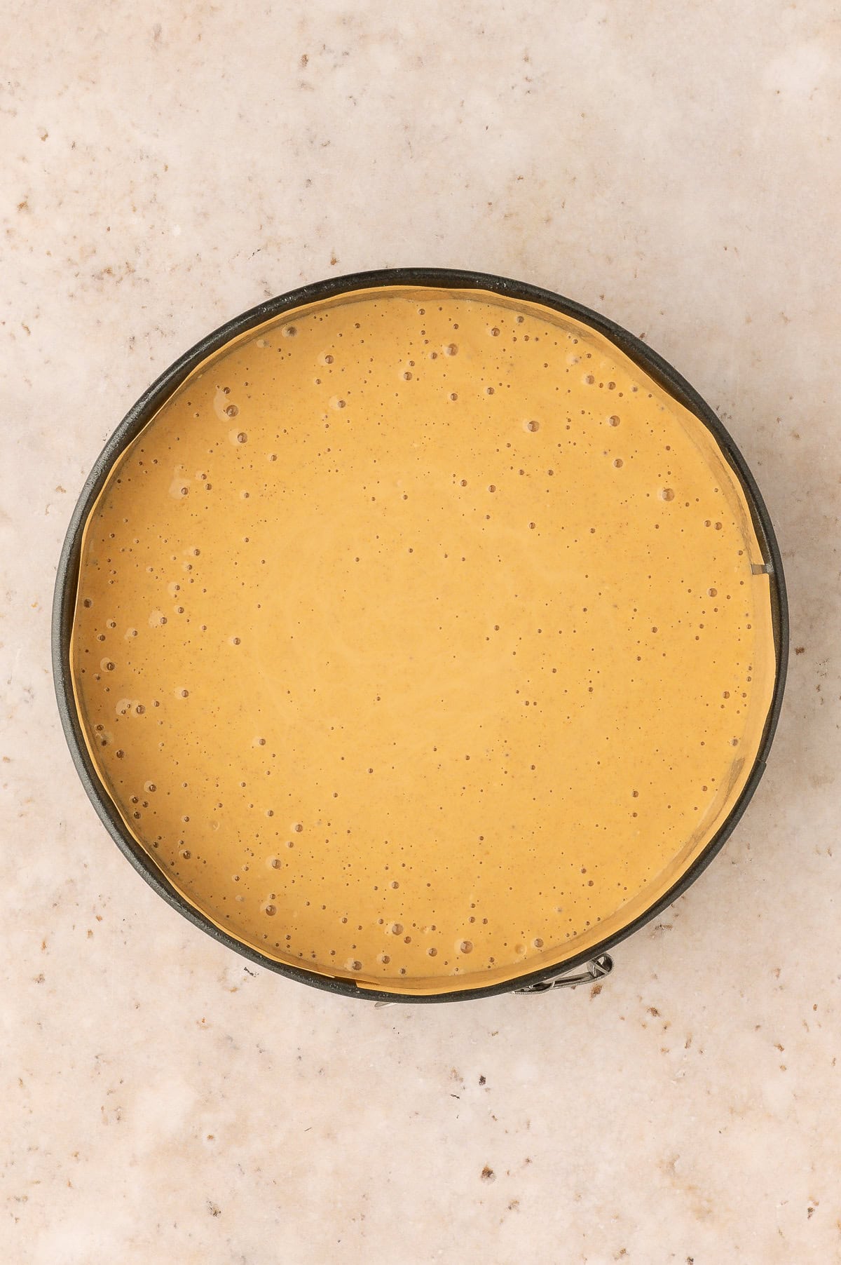 Blended ingredients for protein pumpkin cheesecake poured into a 6-inch springform pan.
