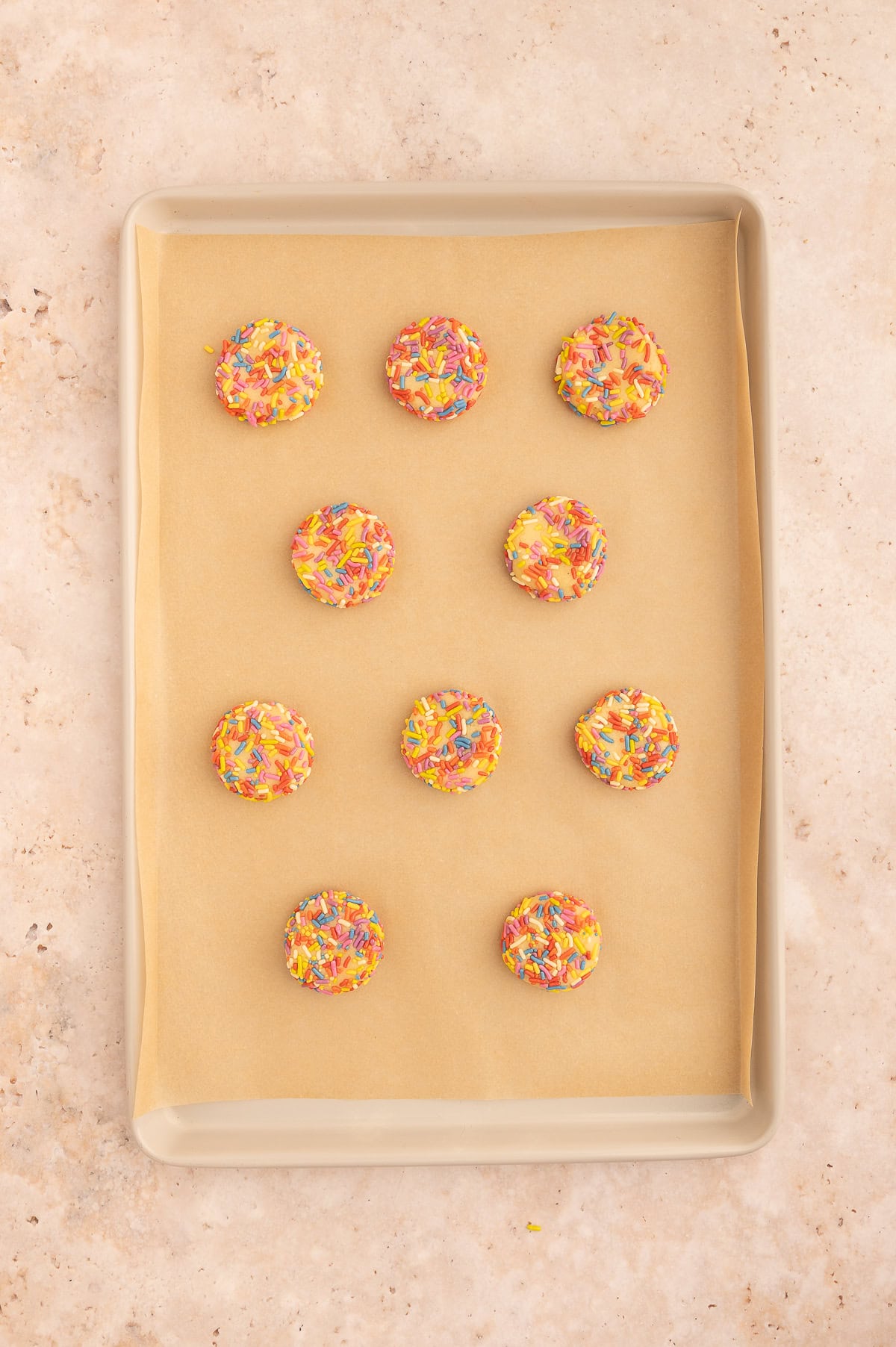 Flattening unbaked almond flour sugar cookies on a baking sheet.