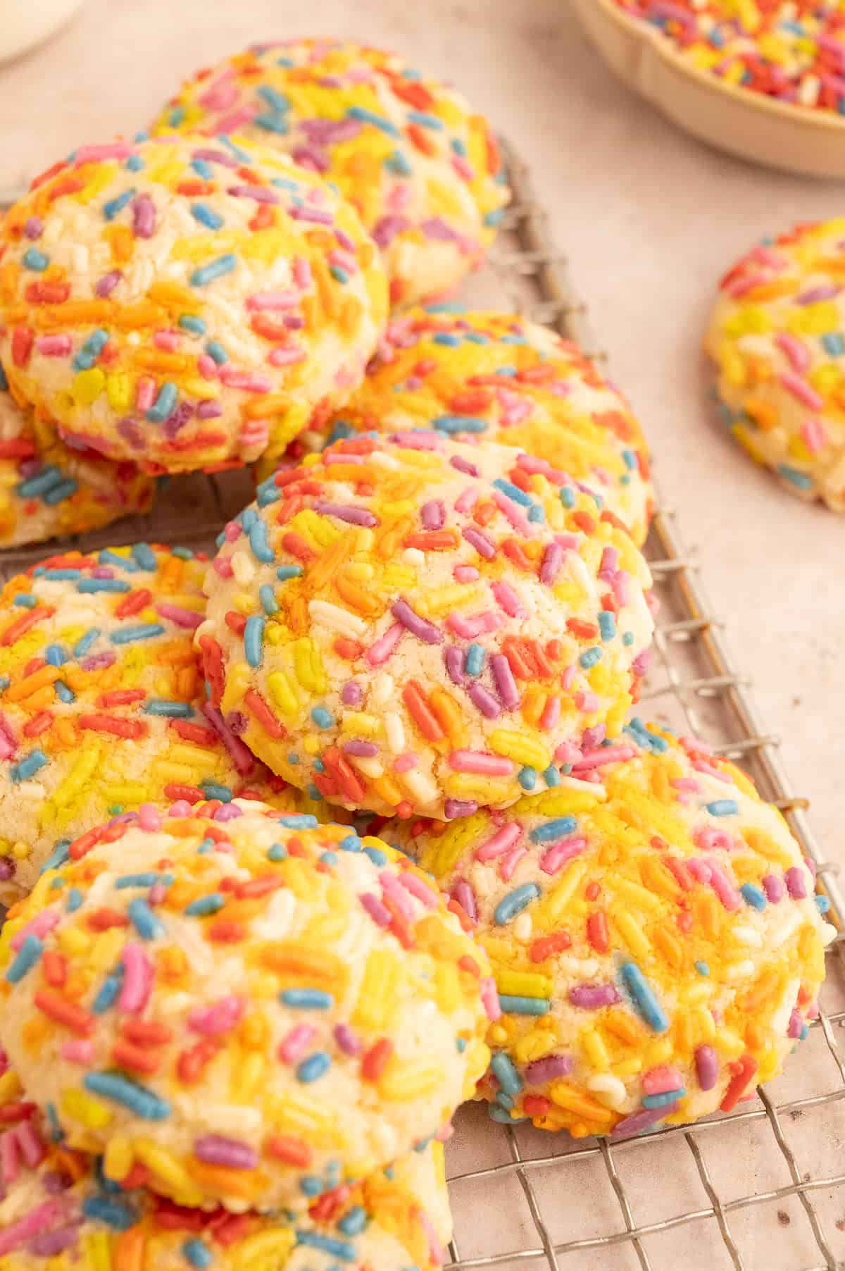 Almond flour sugar cookies coated with sprinkles on a cooling rack.