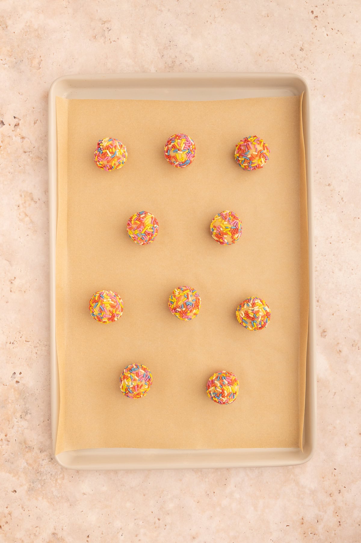 Dough balls for almond flour sugar cookies on a baking sheet.