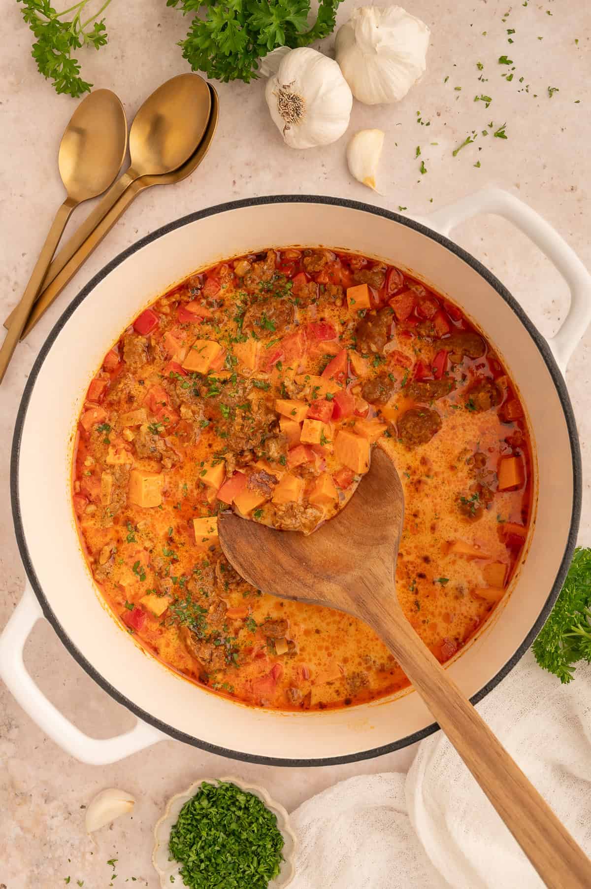 Pot of sweet potato and chorizo soup with a serving spoon in it.