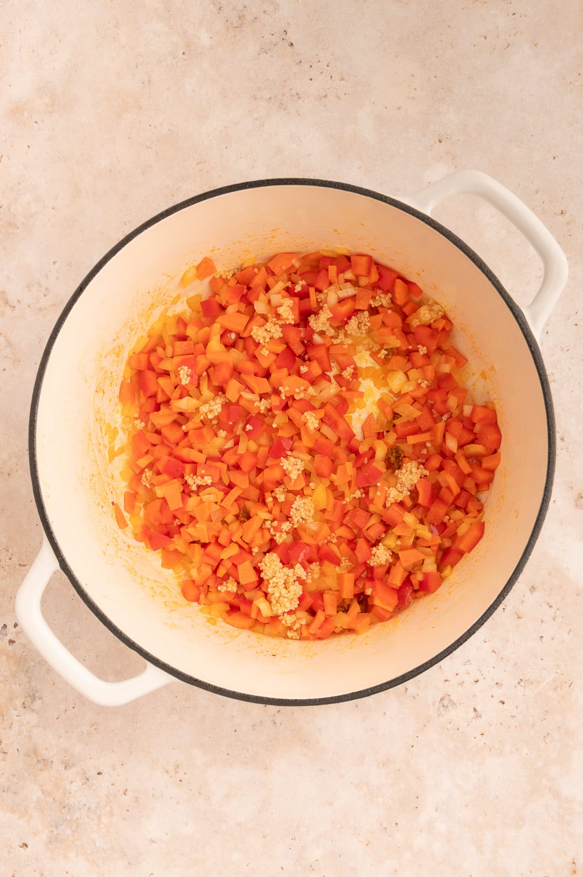 Garlic added to stock pot with onions, peppers, and carrots.