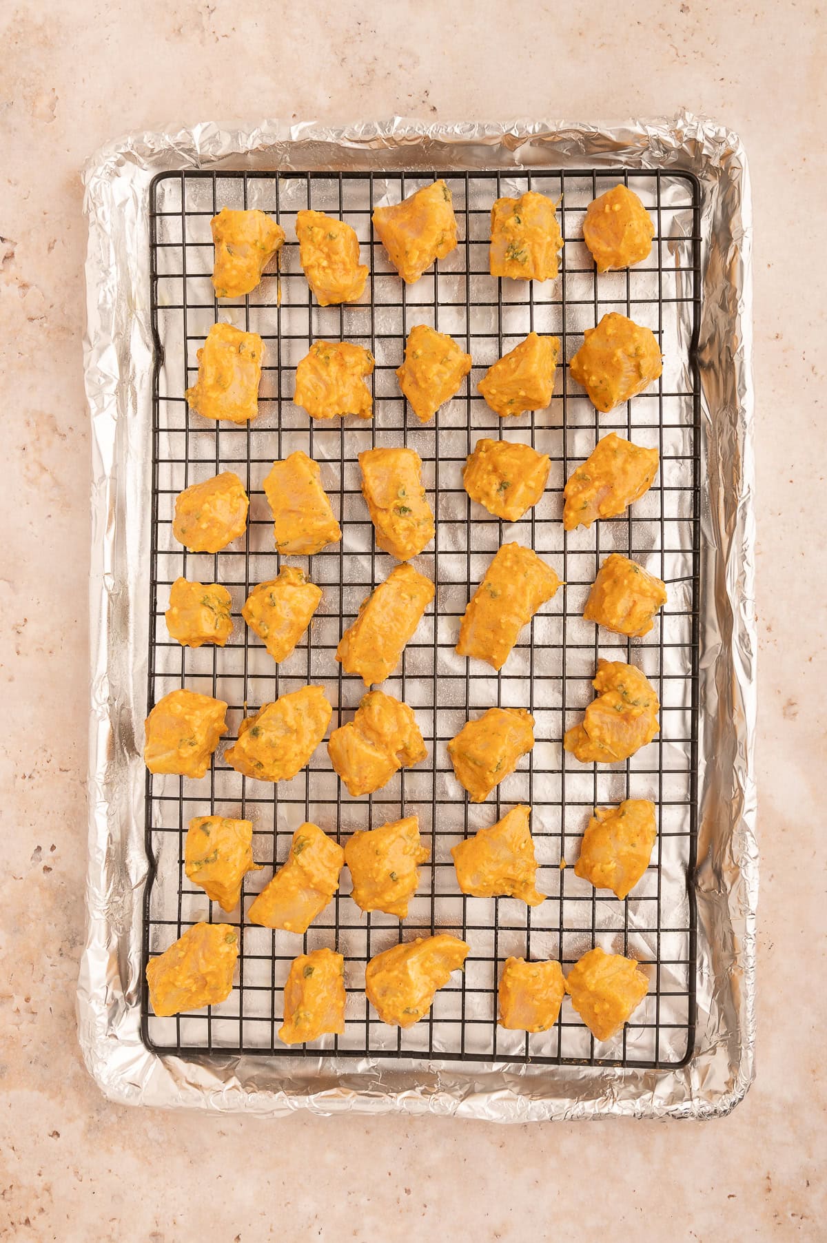 Uncooked tikka chicken on a baking sheet.