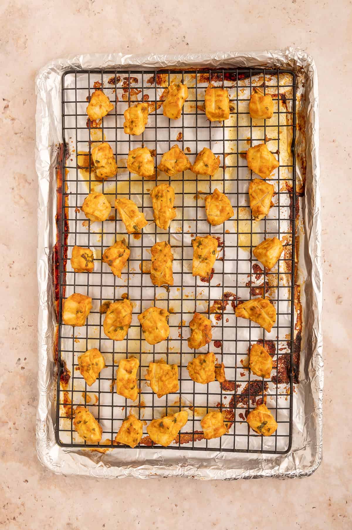 Cooked tikka chicken on a baking sheet.