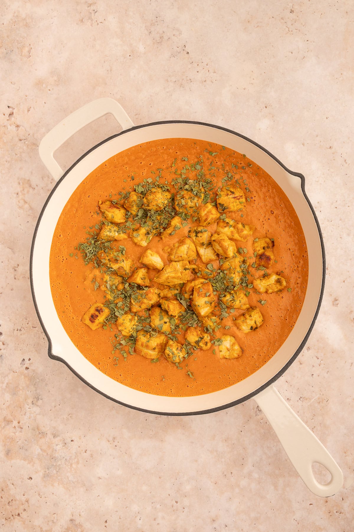 Adding cooked chicken and herbs to finish the dairy-free tikka masala.