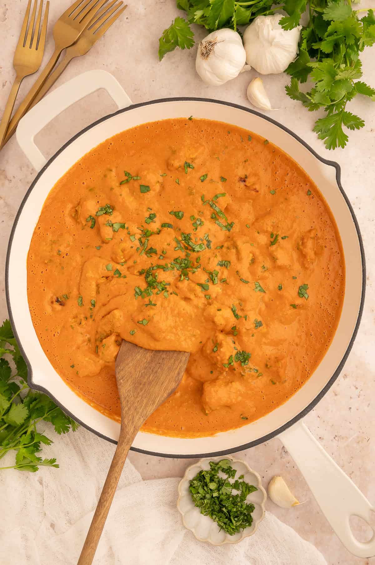 Finished dairy-free tikka masala in a skillet with a wooden spoon in it.