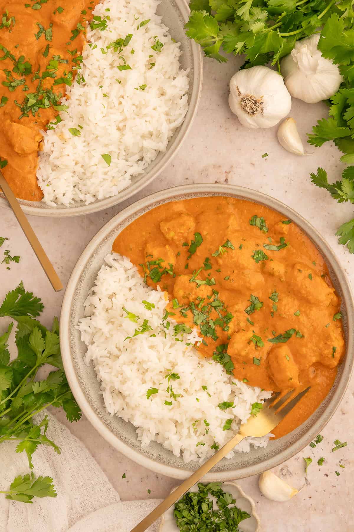 Richly orange colored dairy-free tikka masala in a bowl with rice and a fork in it.