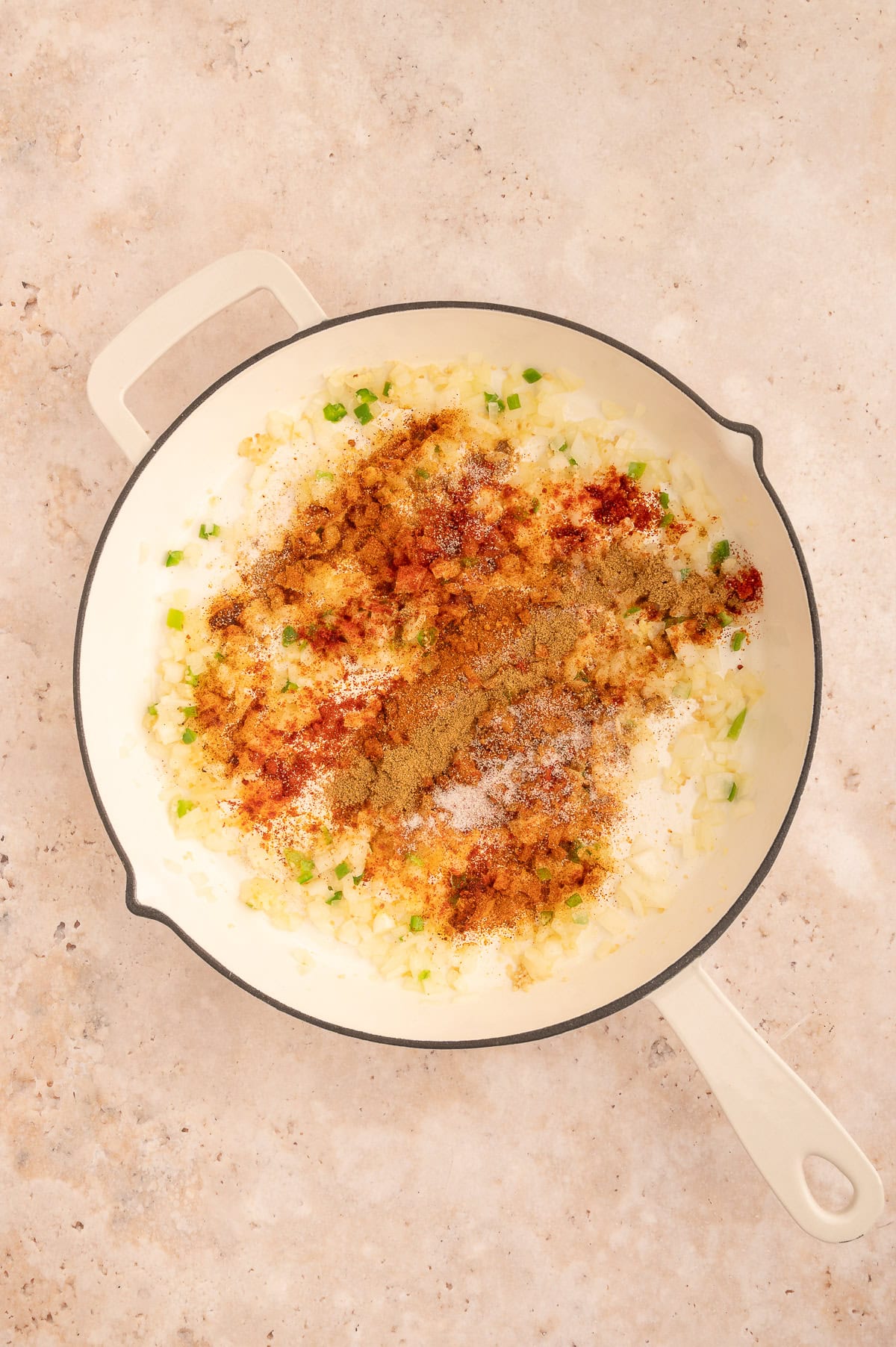 Adding seasonings to the vegetables in the skillet.