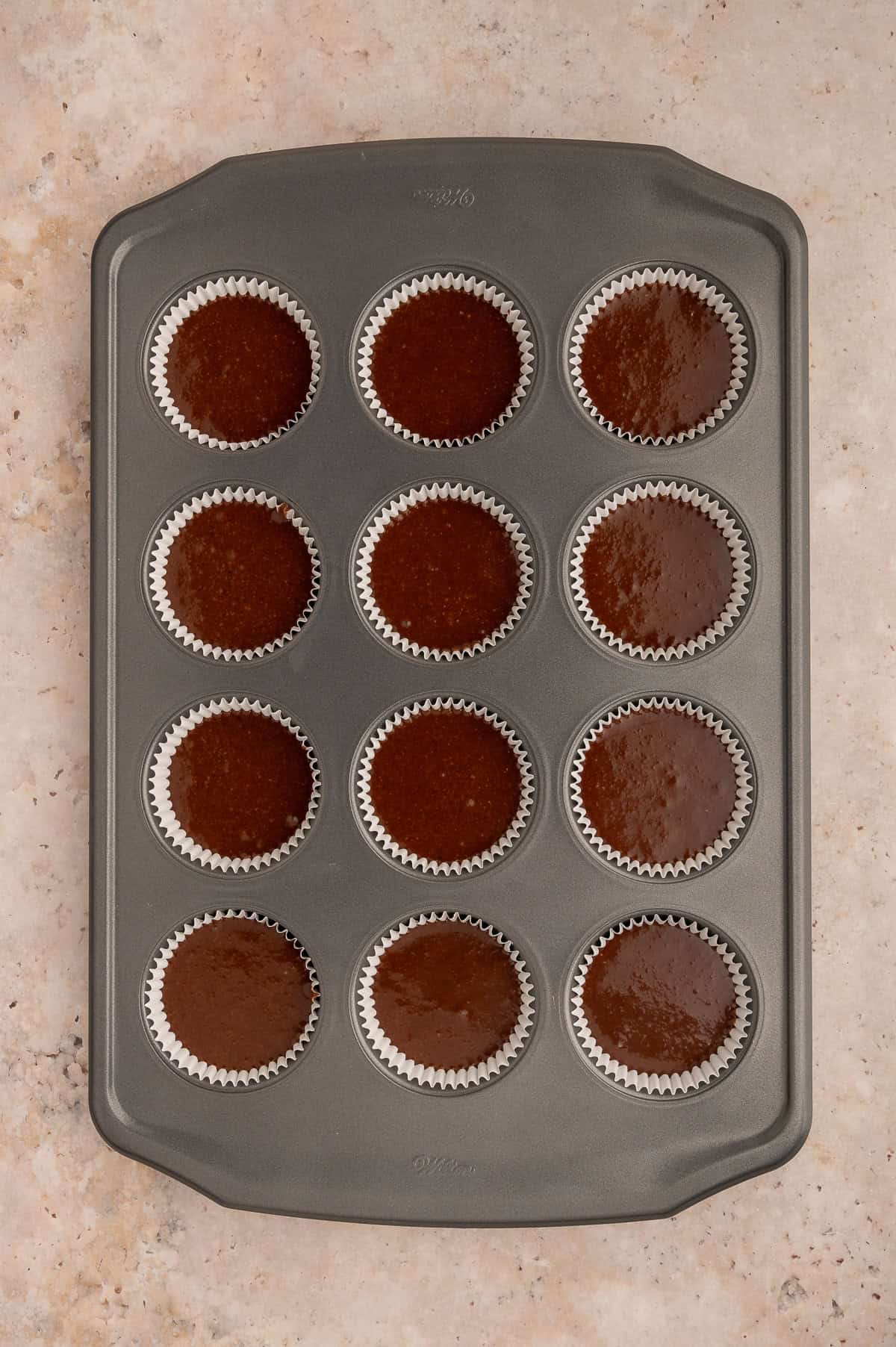 Batter for almond flour chocolate cupcakes divided into a muffin tin.