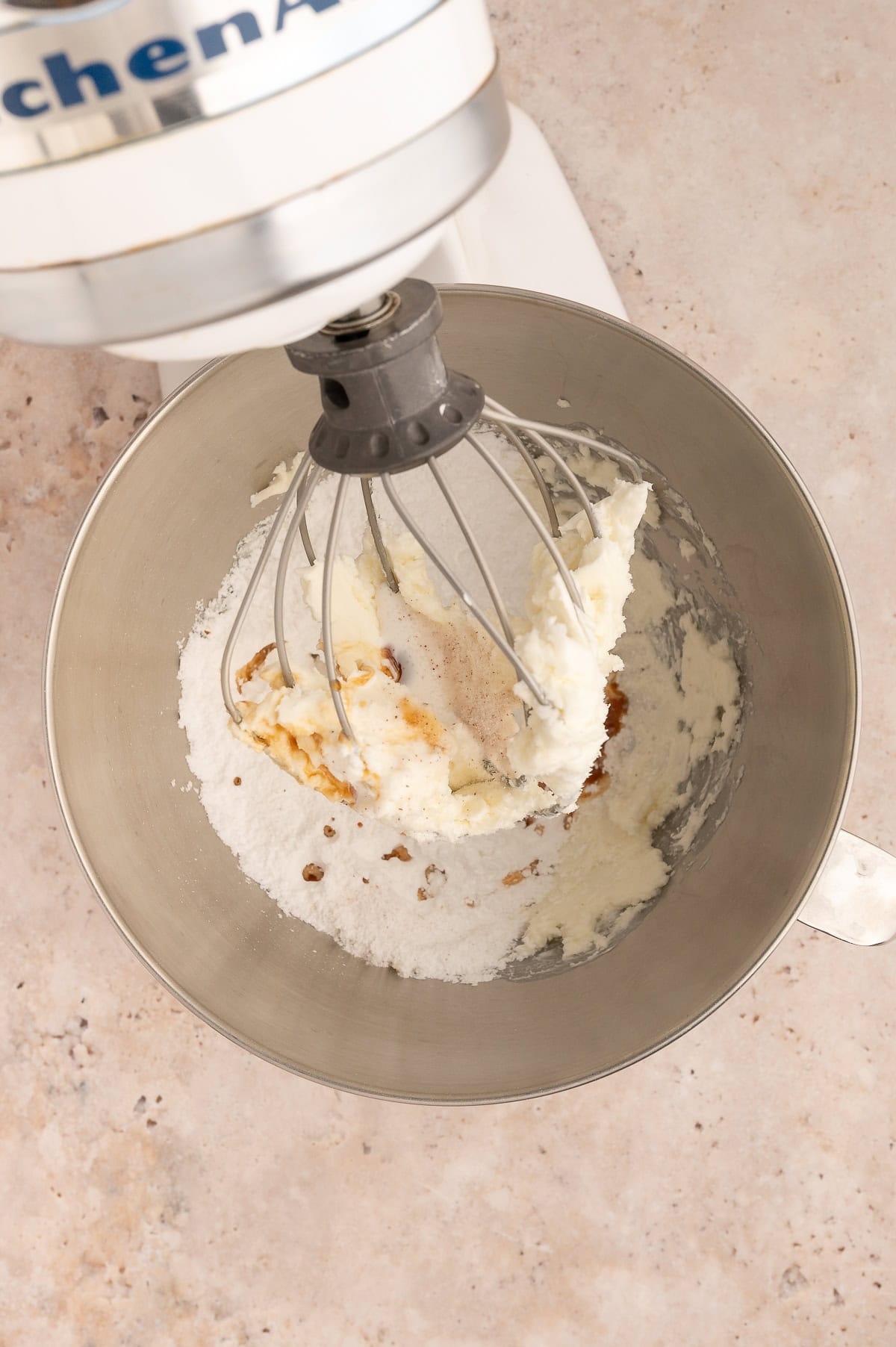 Vanilla, coconut milk, powdered sugar, and salt being added to the stand mixer with the palm shortening.